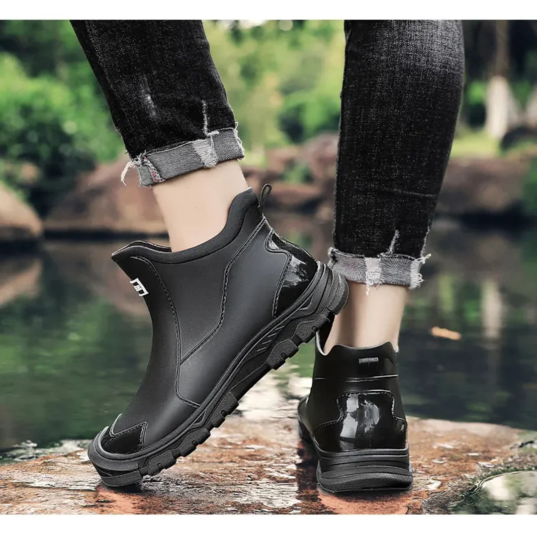 Men's black rain boots on a riverside path