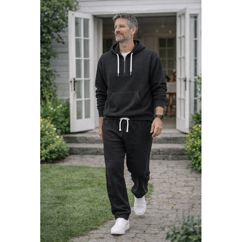 Man walking in black hooded tracksuit with joggers
