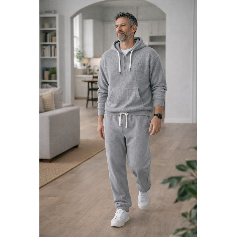 Man walking in grey hooded tracksuit indoors