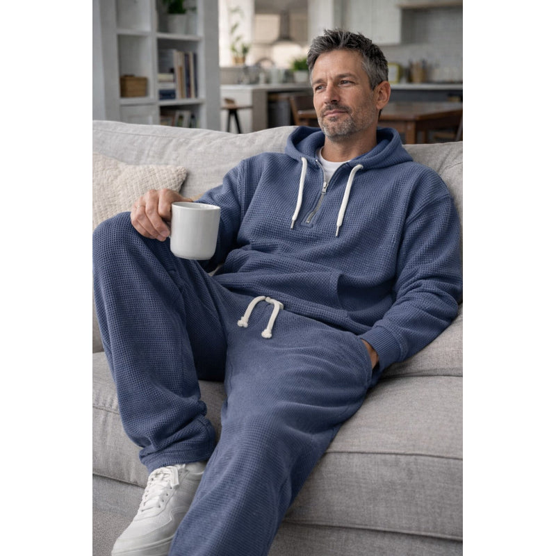Man seated in dark blue hooded tracksuit
