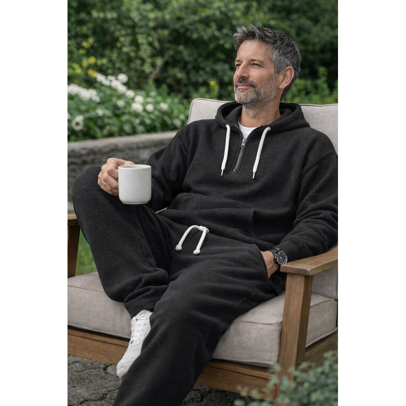 Man relaxing outdoors in black hooded tracksuit
