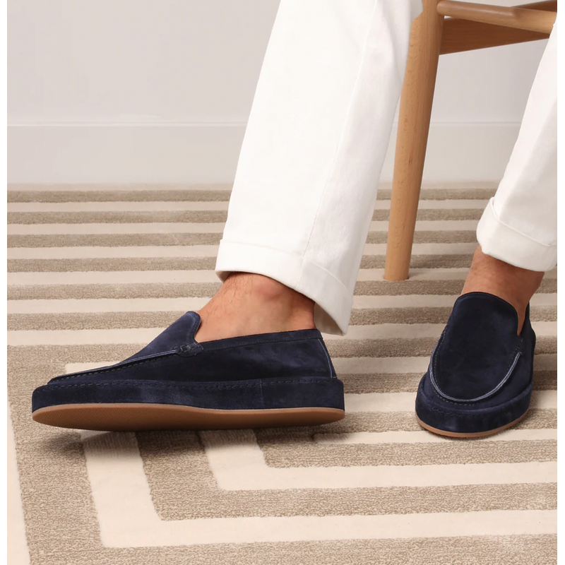 Navy men's slip-on loafers worn with white trousers