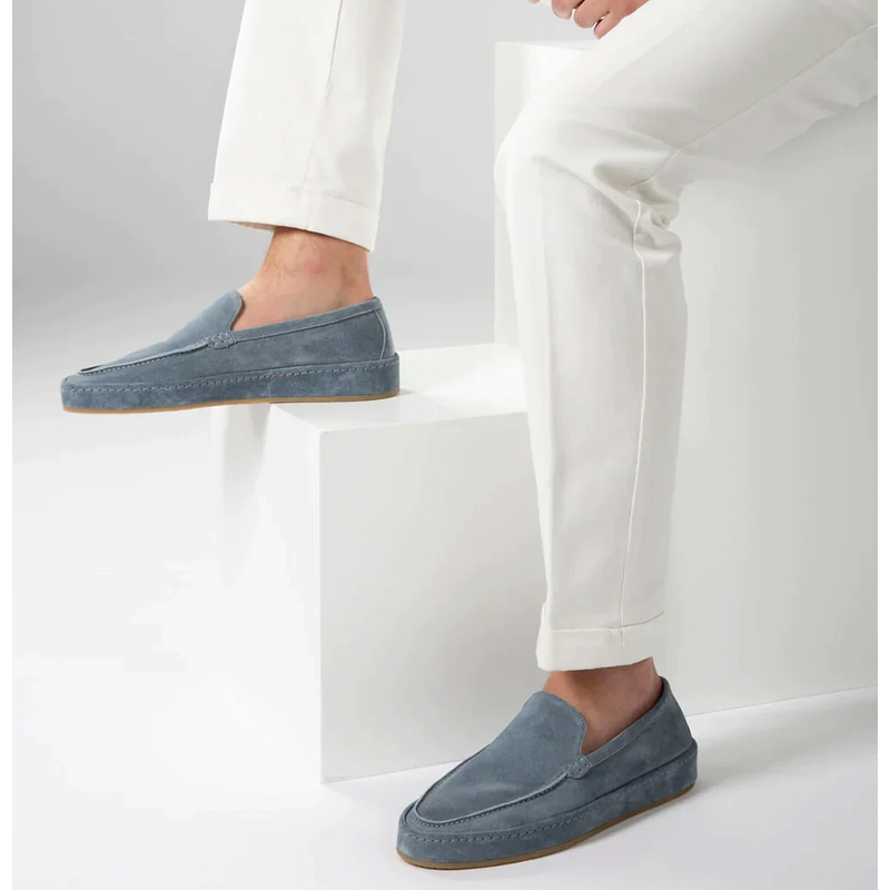 Light blue men's slip-on loafers worn with white trousers