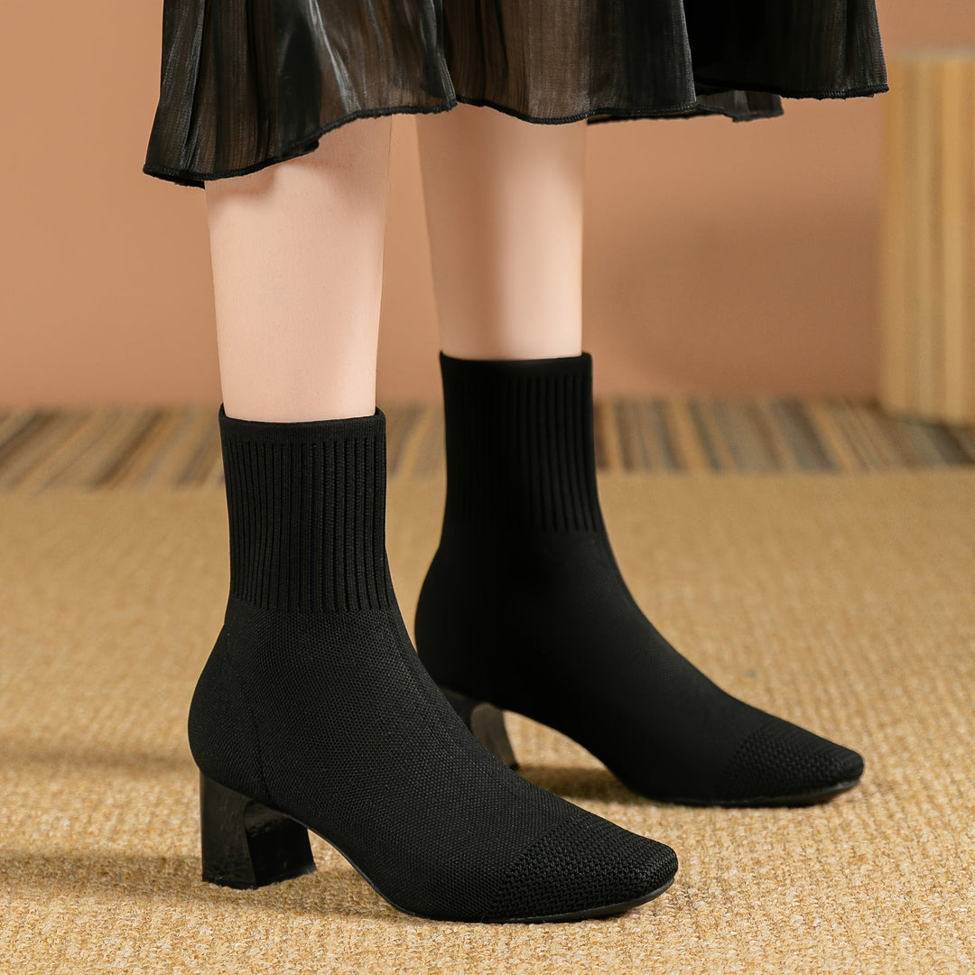 Woman wearing black knit sock boots with a skirt