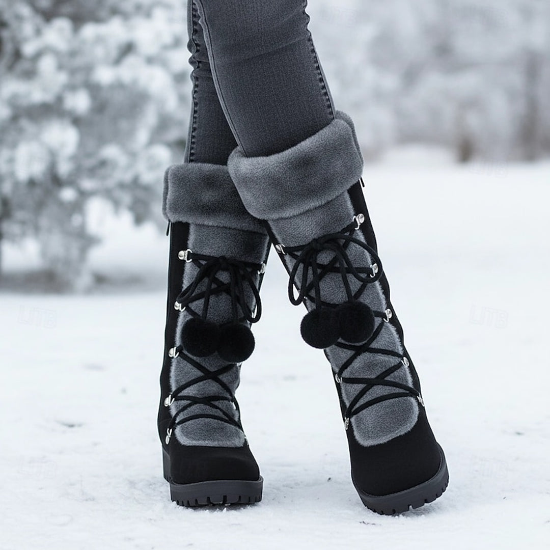 Women's black pom-pom winter boots worn in the snow