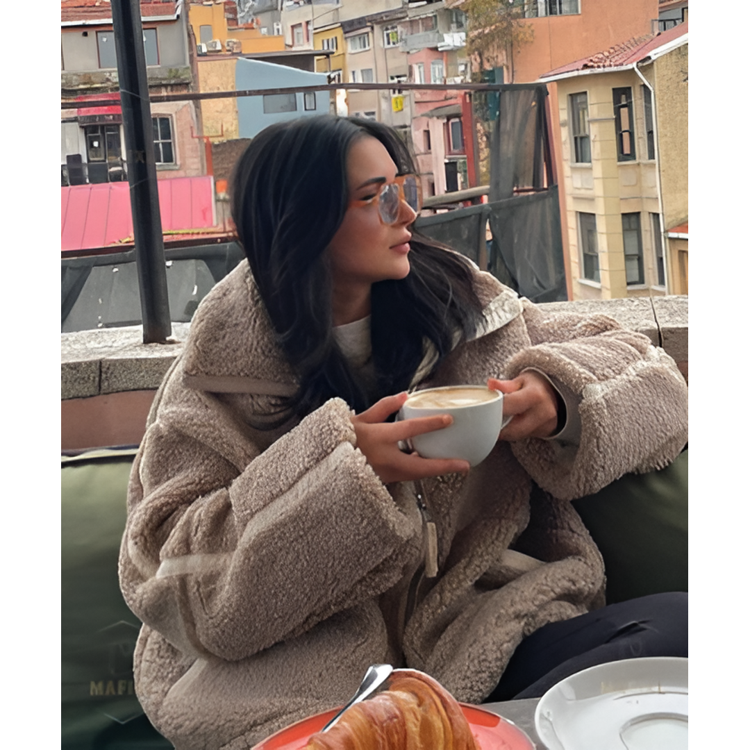 Woman in a taupe oversized teddy jacket at a café