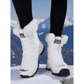 Women's white quilted lace-up snow boots in the mountains