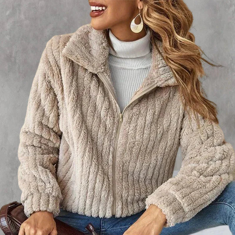Woman seated in a beige plush zip-up jacket