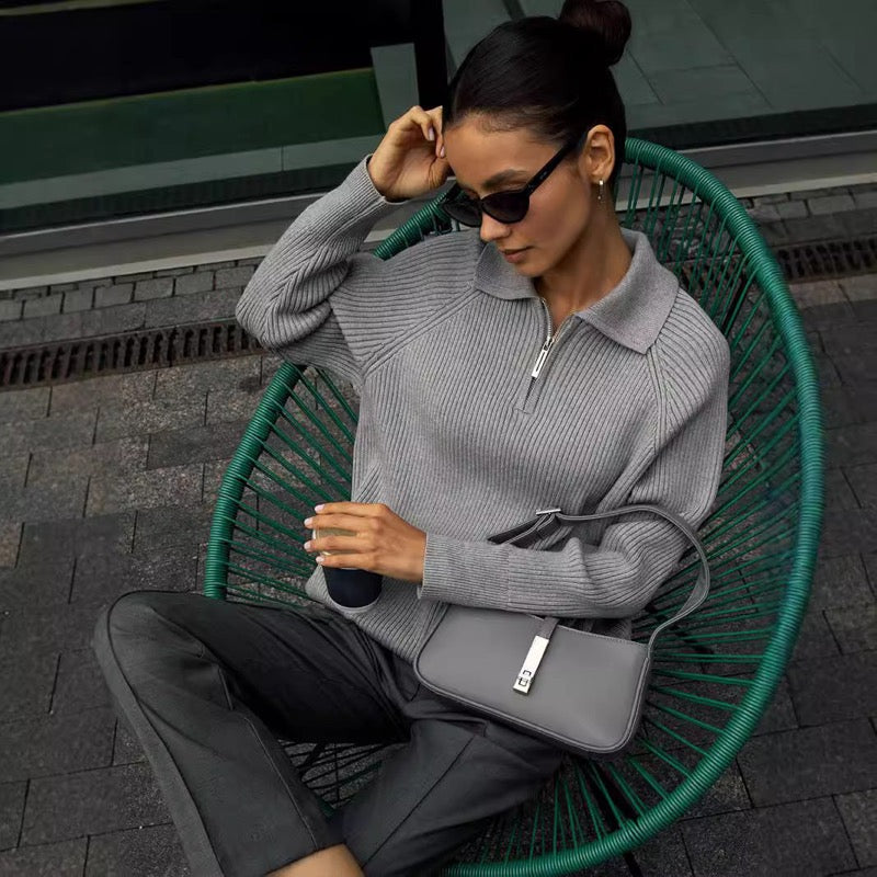 Woman seated in a grey ribbed zip-neck sweater
